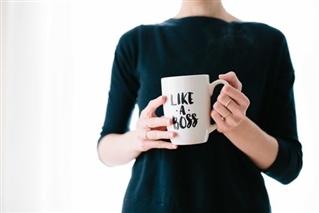 Woman holding coffee cup printed with 'Like A Boss' on it.