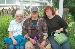 Kris Lescinsky and her parents sitting in a garden.